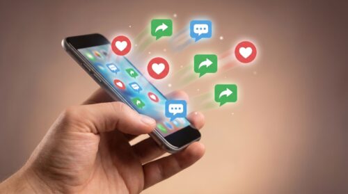 Qué es el engagement en redes sociales: iconos de me gusta y comentarios saliendo de un móvil