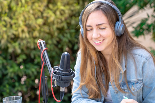 mujer atractiva grabando podcast radio chica joven hablando sesion transmision vivo al aire libre scaled