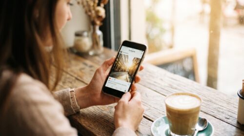 Chica en una cafetería eligiendo una frase para una foto de Instagram en su móvil